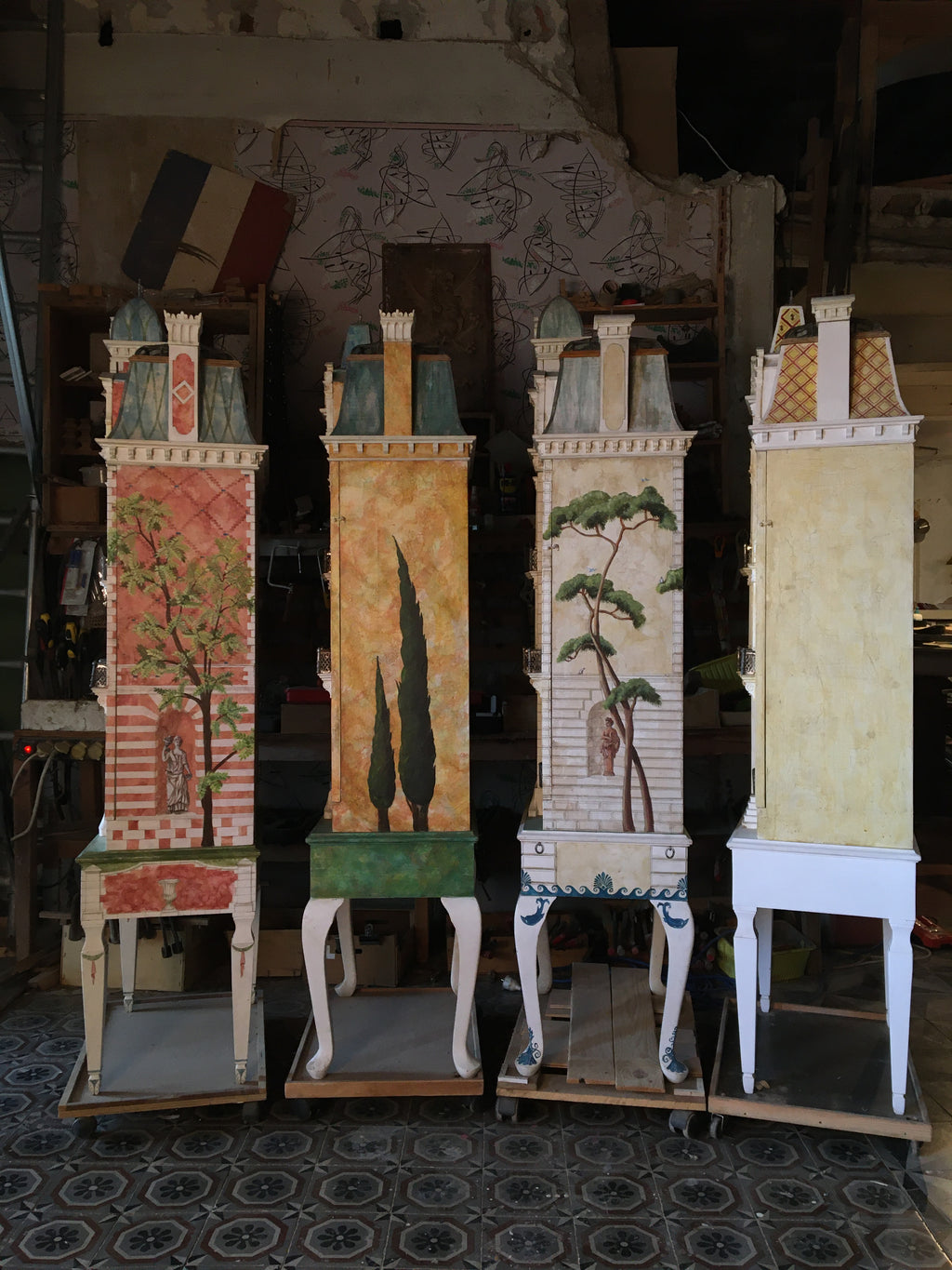 Four one-of-a-kind Second Empire dollhouses showing hand-painted tree murals and architectural side elevations in the studio.