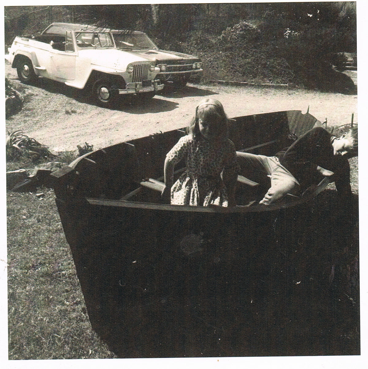 Eric Lansdown’s sister seated in the handmade dinghy he built for her at age eight, an early example of his boatbuilding craft.