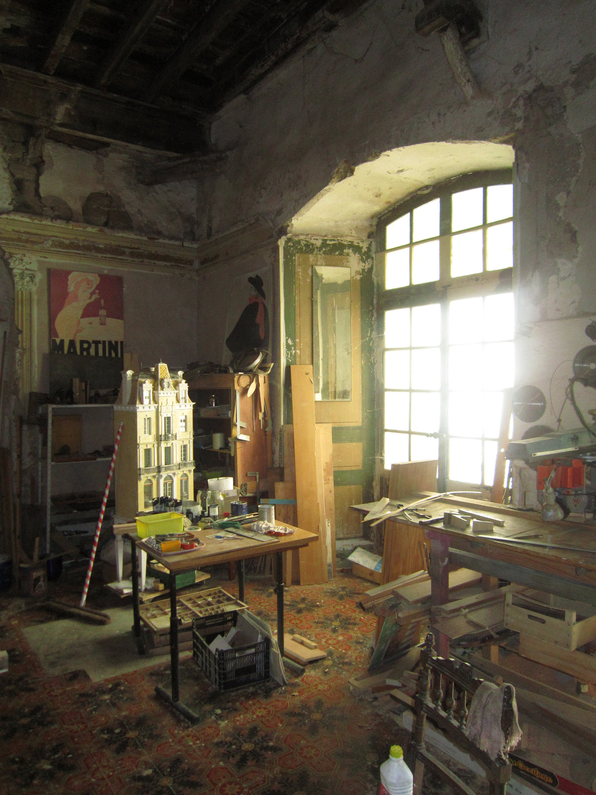 Interior of the Lansdown Arts studio in a medieval bishop’s hall in Gabian, France, with a handmade architectural dollhouse, worktables and traditional tools.