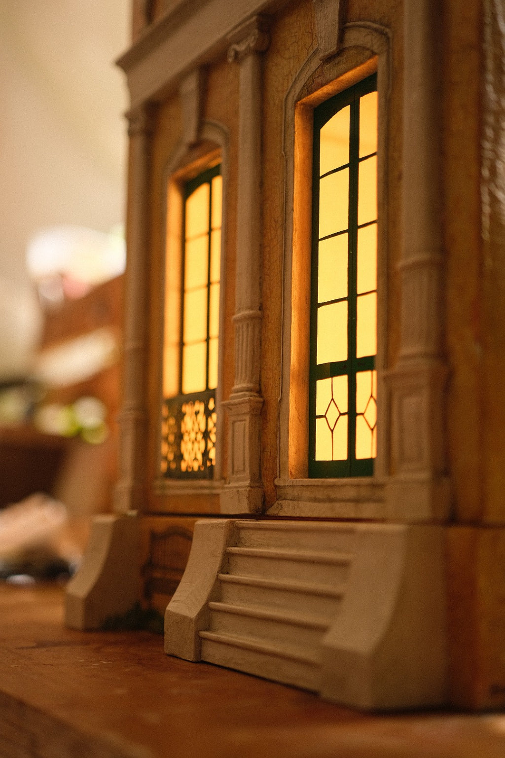 Illuminated arched windows, classical pilasters and ornate metal balcony detail on Piccolo Toscano, a handcrafted luxury architectural dollhouse.
