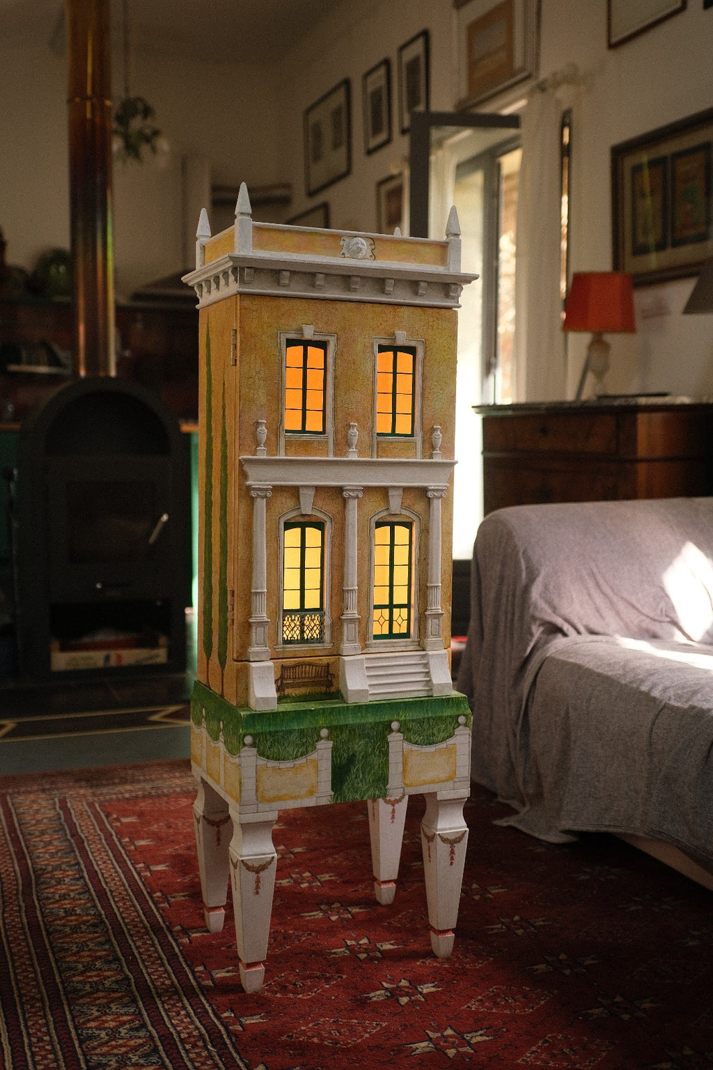 Piccolo Toscano, a tall handcrafted Tuscan architectural dollhouse by Eric Lansdown with illuminated windows, classical columns and a painted garden base.