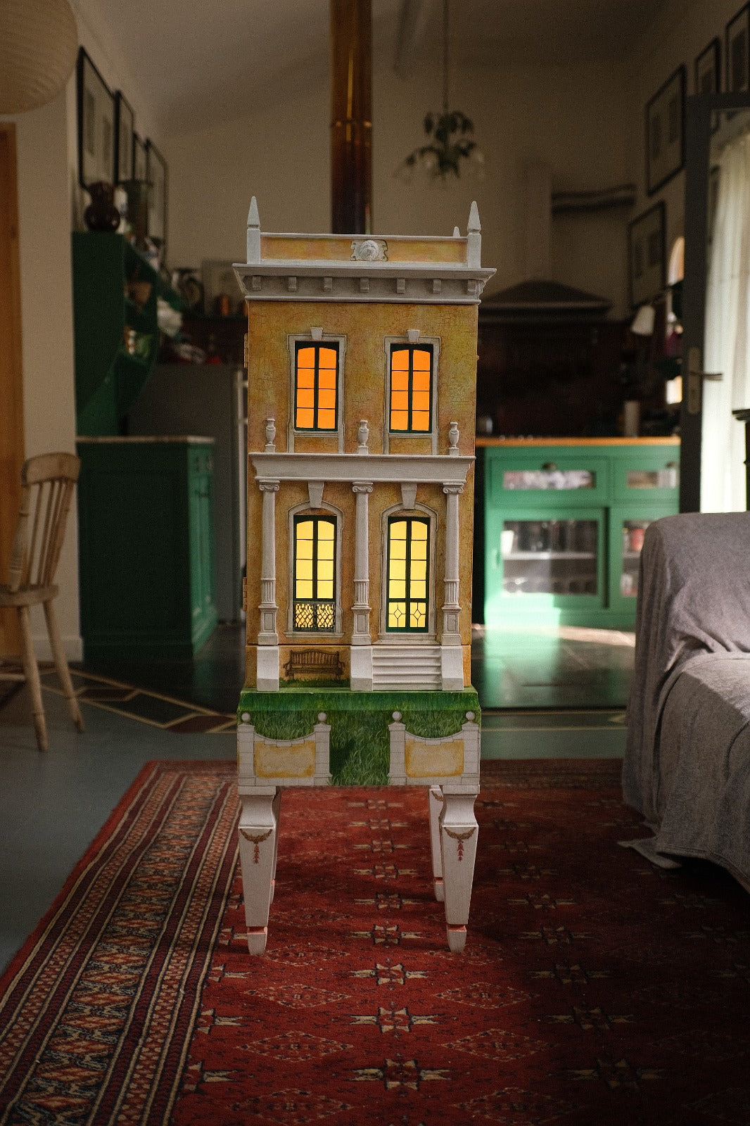 Front view of Piccolo Toscano, an illuminated handcrafted architectural dollhouse and miniature manor with classical columns, metal balconies and painted legs.