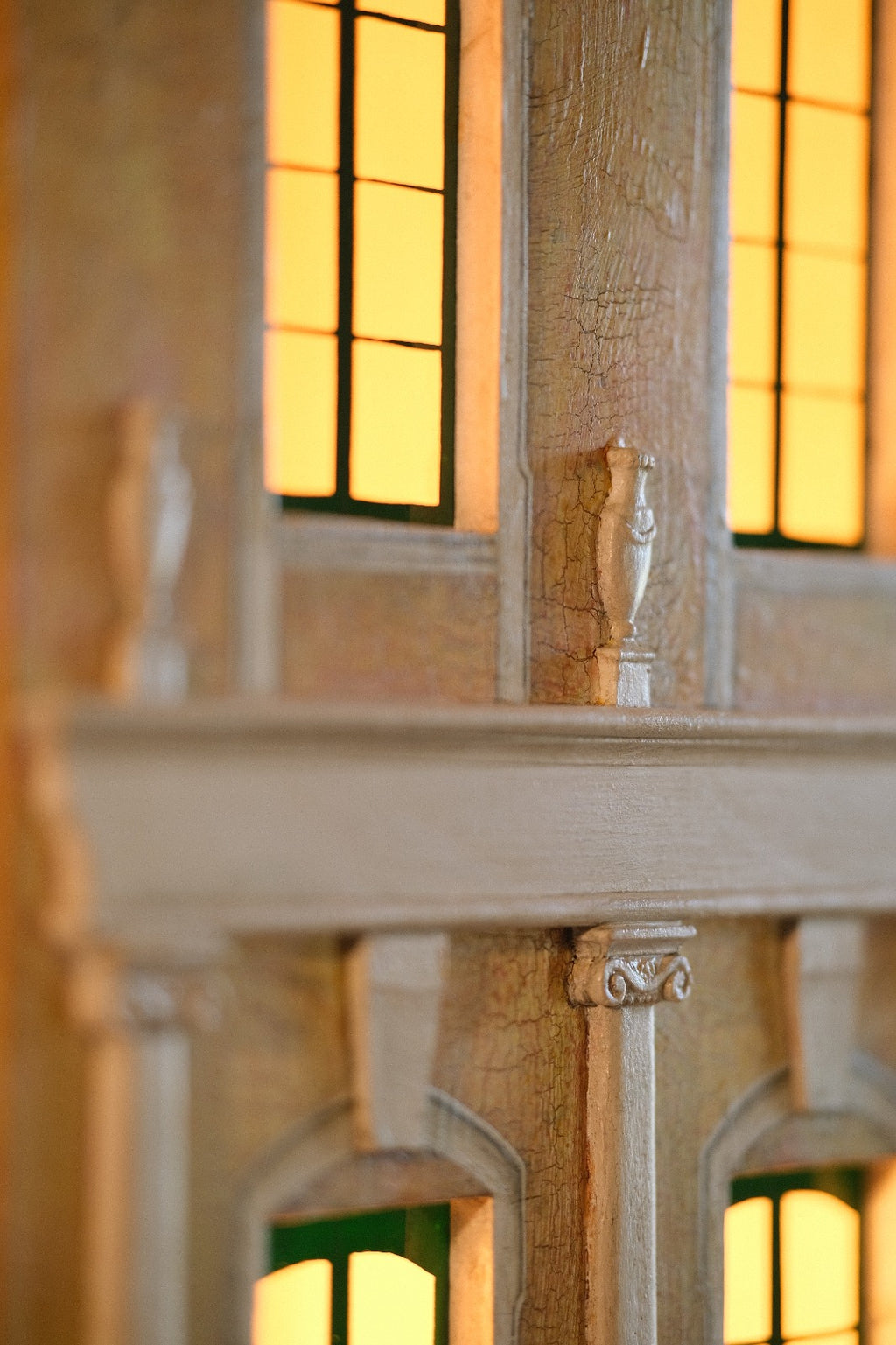 Crackled hand-painted façade, miniature classical urns and ornamental columns on Piccolo Toscano, highlighting traditional decorative art and aged finishes.
