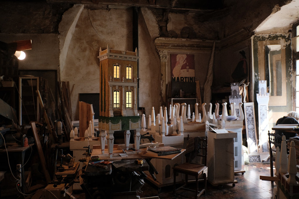 Illuminated Piccolo Toscano architectural dollhouse on Eric Lansdown’s workbench in southern France, surrounded by tools and handcrafted components.