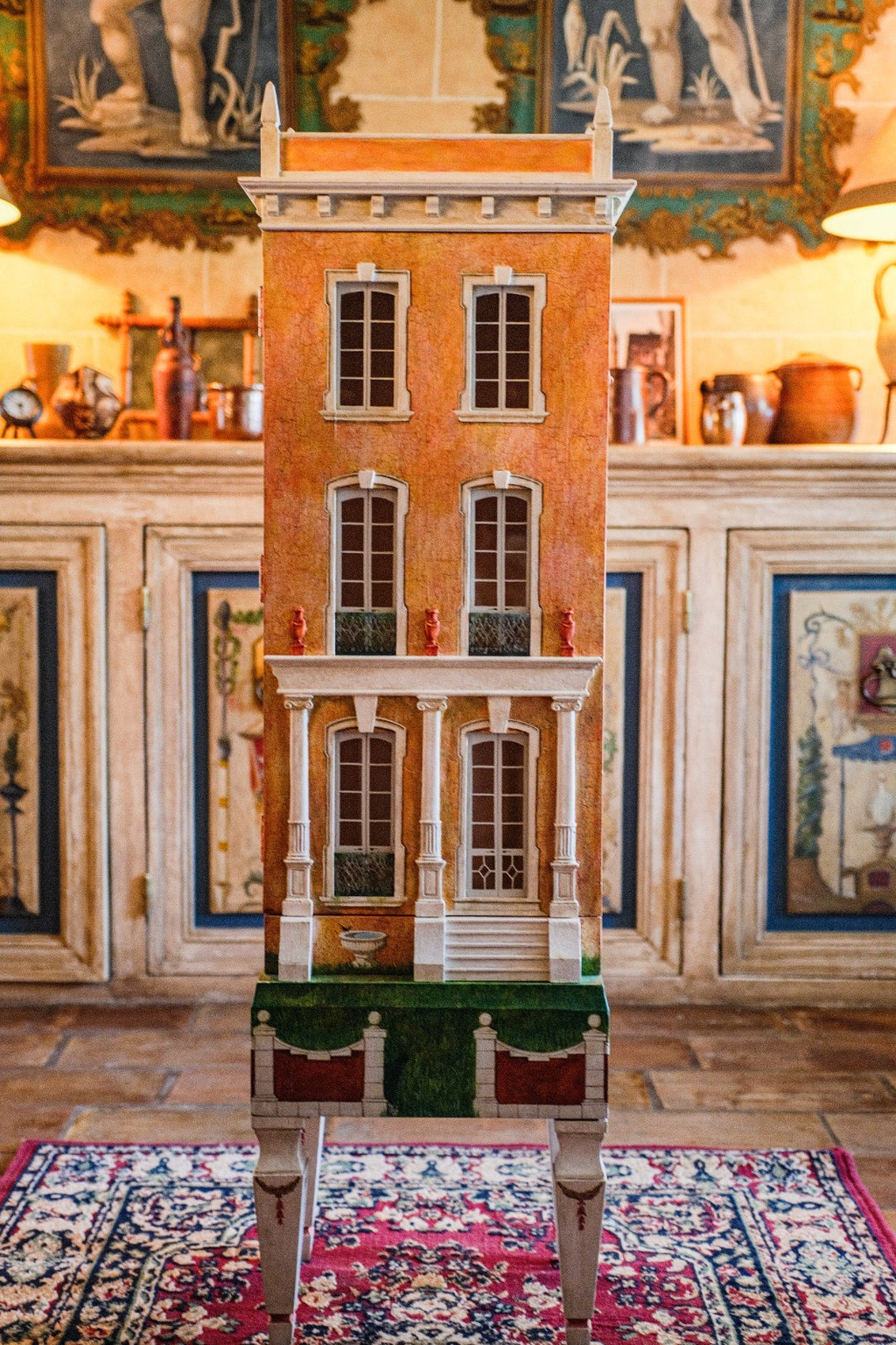 Close-up of Cypress House, a bespoke artisan dollhouse with orange façade, classical columns and white-trimmed windows
