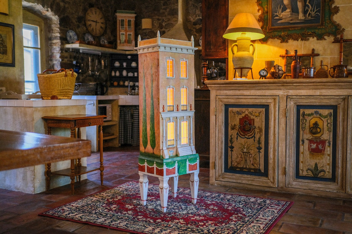 Tall orange Cypress House, a handmade architectural dollhouse displayed as collectible art in a French country interior