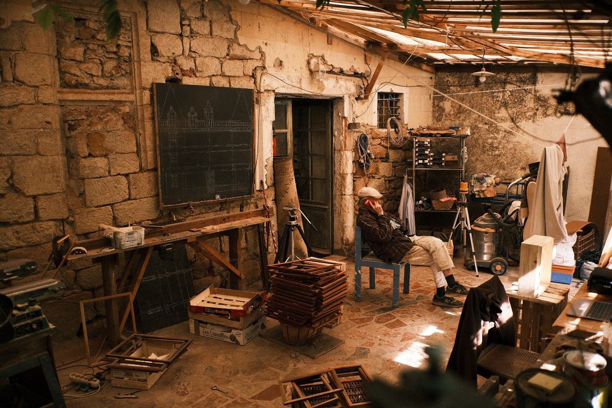 Traditional French craft workshop with architectural drawings, wooden frames and tools for bespoke miniature dollhouses