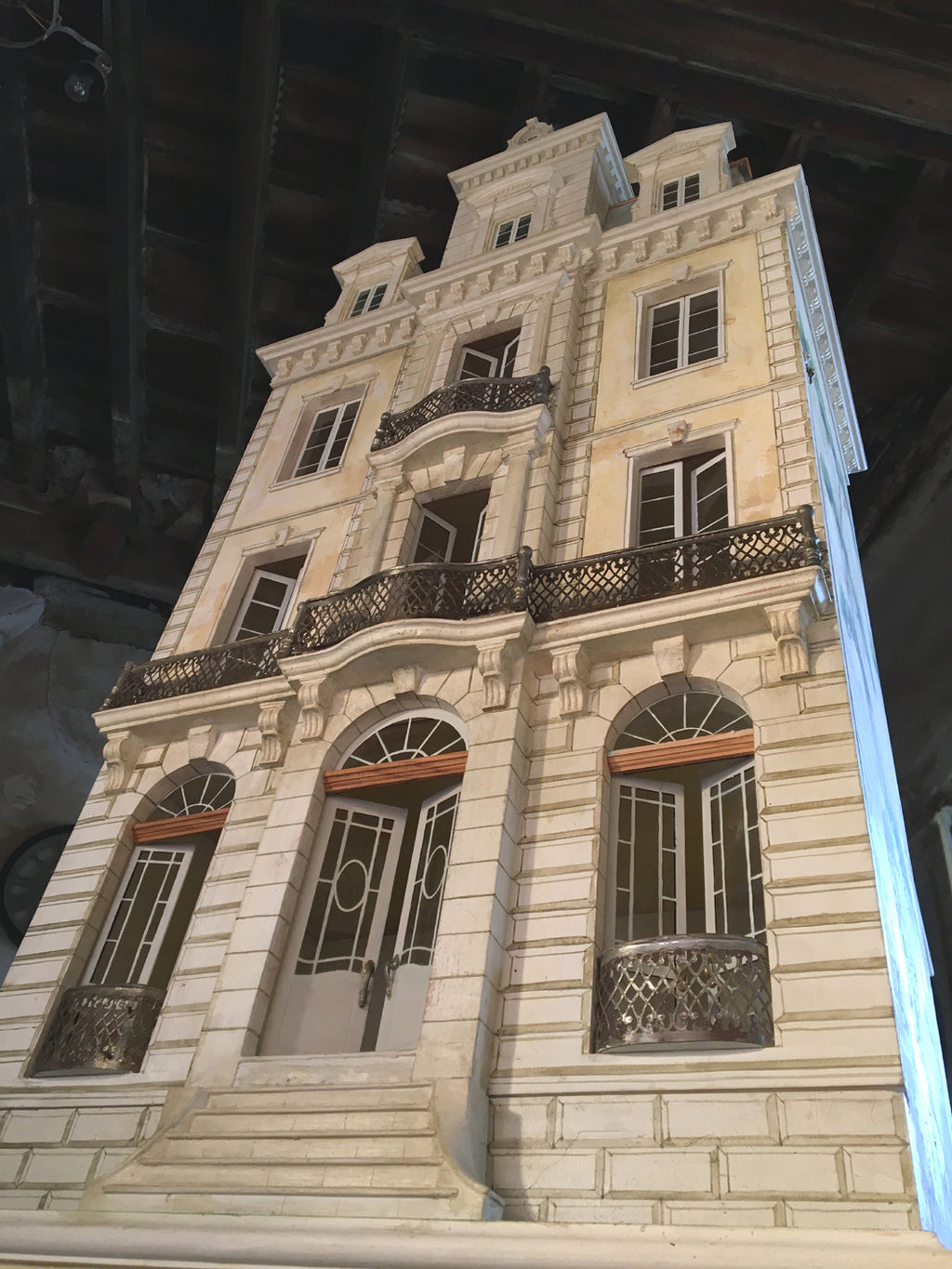 Street-level view of the tall Whitestone dollhouse, inspired by a Parisian townhouse with wrought-metal balconies.